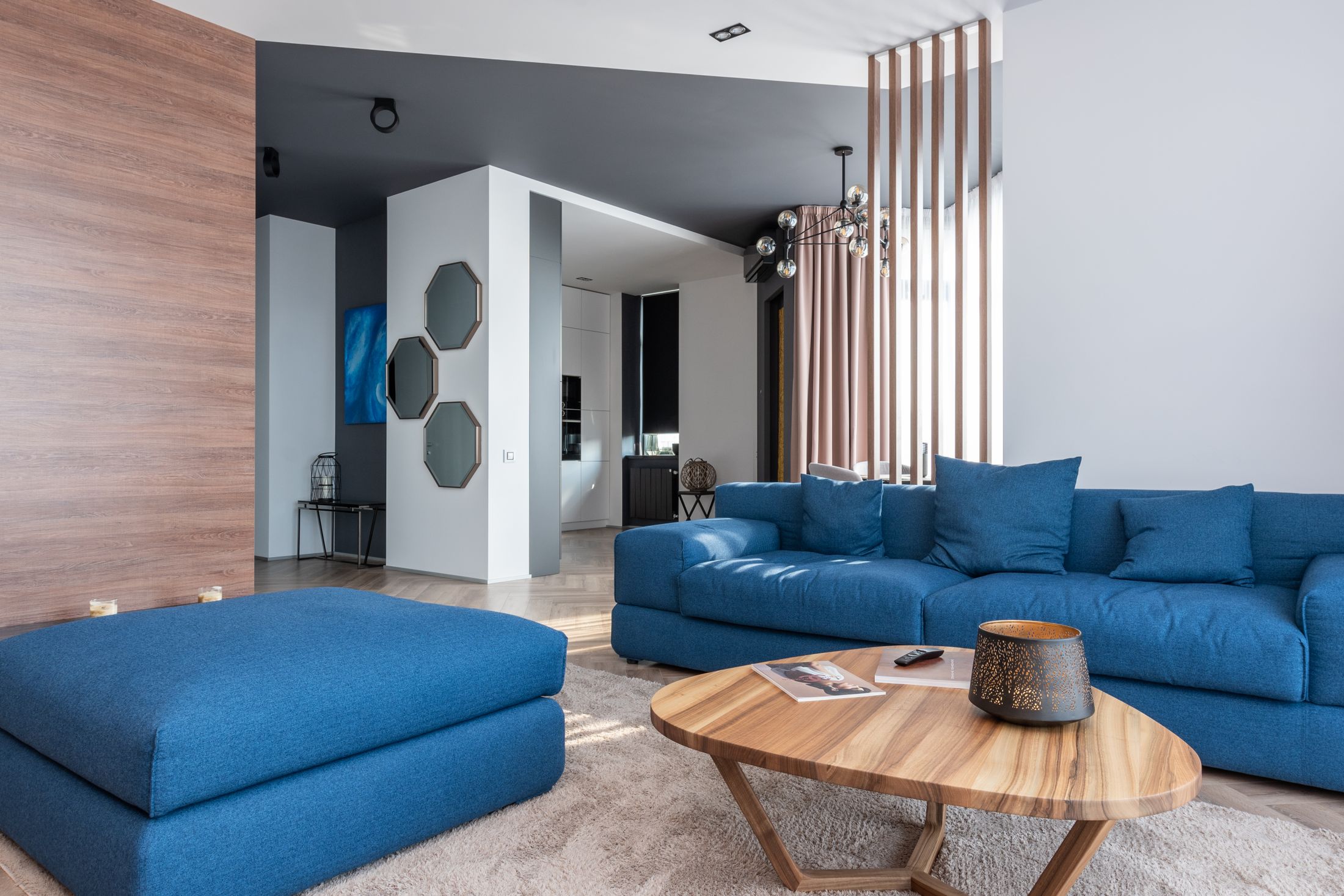 Un salon contemporain avec canapé bleu, table en bois et cloison ajourée